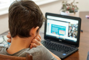 Boy looking at computer with hands holding his neck